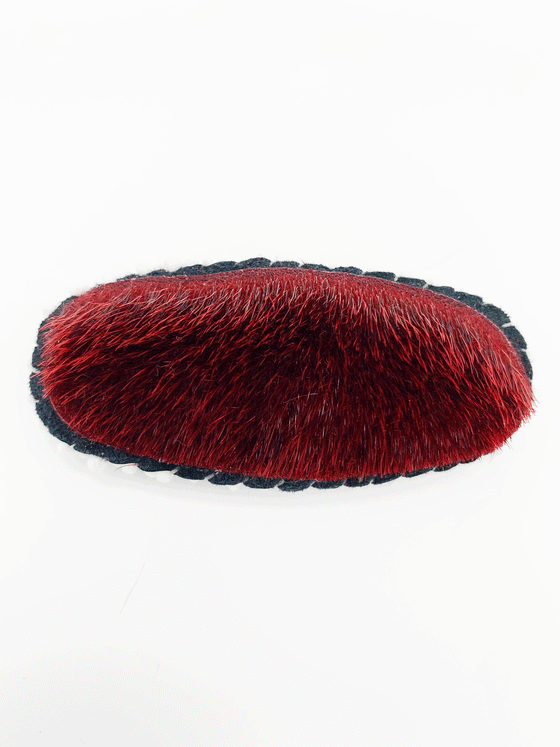 dyed red sealskin in the shape of an oval hair clip.