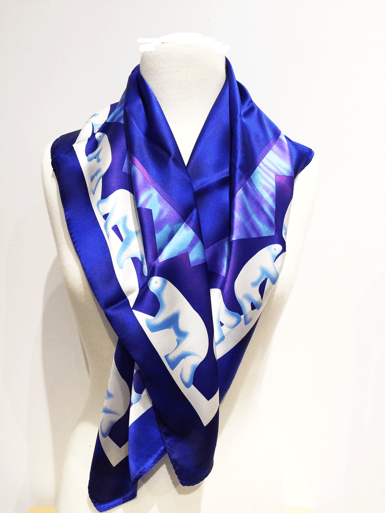 Pictured here is a royal blue silk scarf with light blue and white accents. Featured on the scarf is the majestic Canadian polarbear.