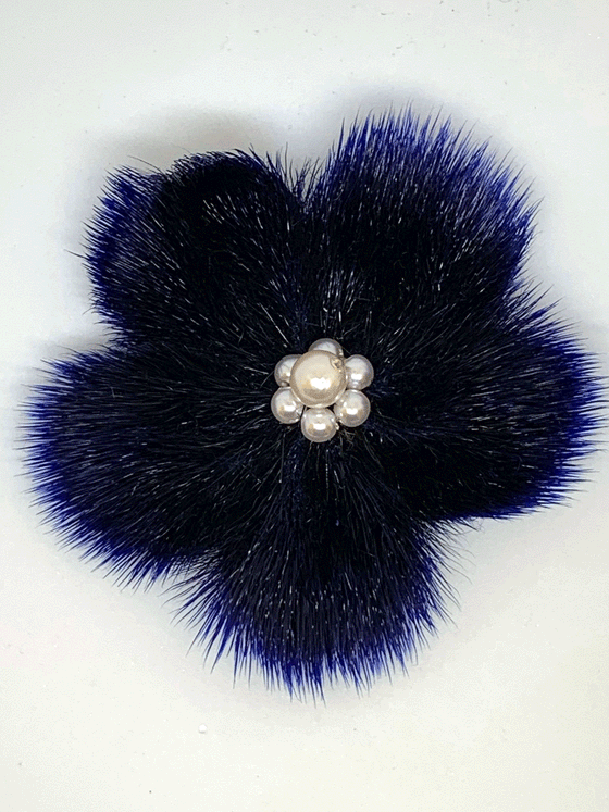 sealskin in the shape of a dark blue flower, with 6 small and one big white pearl like circles in the center.