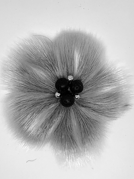 sealskin in the shape of a grey flower, with several pearl like circles in the center.