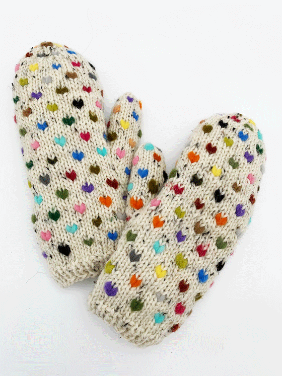 An ecru pair of knit mittens with small colourful hearts. Colours consist of red, green, brown, blue, yellow, orange, purple and pink.