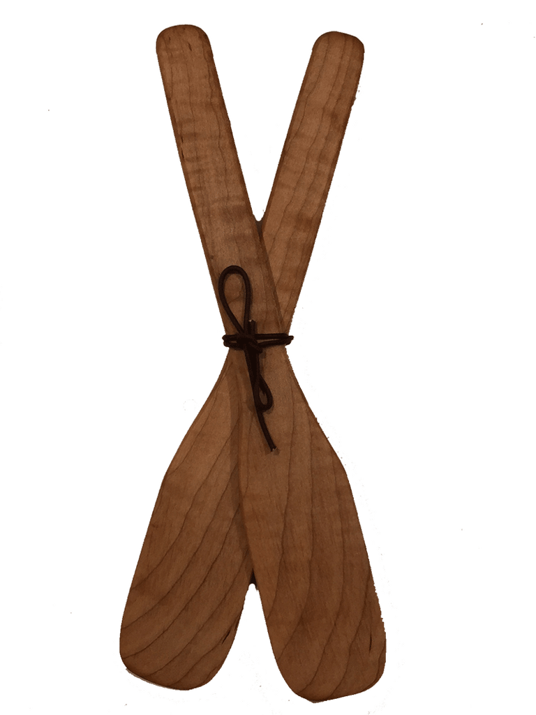 Two paddle-shaped wooden serving spoons crossed in the center and tied with leather cord. The wood's natural colour and grain give each paddle a unique appeal.