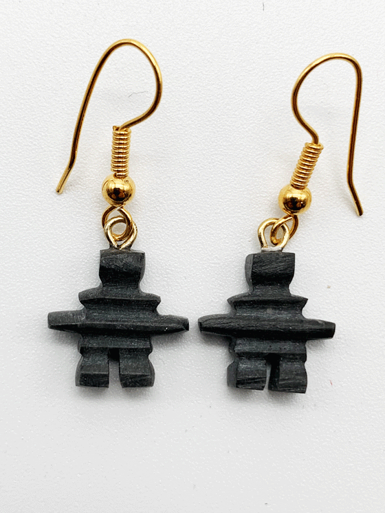 Dangling earrings featuring a small dark grey inuksuk hanging on a gold hook.