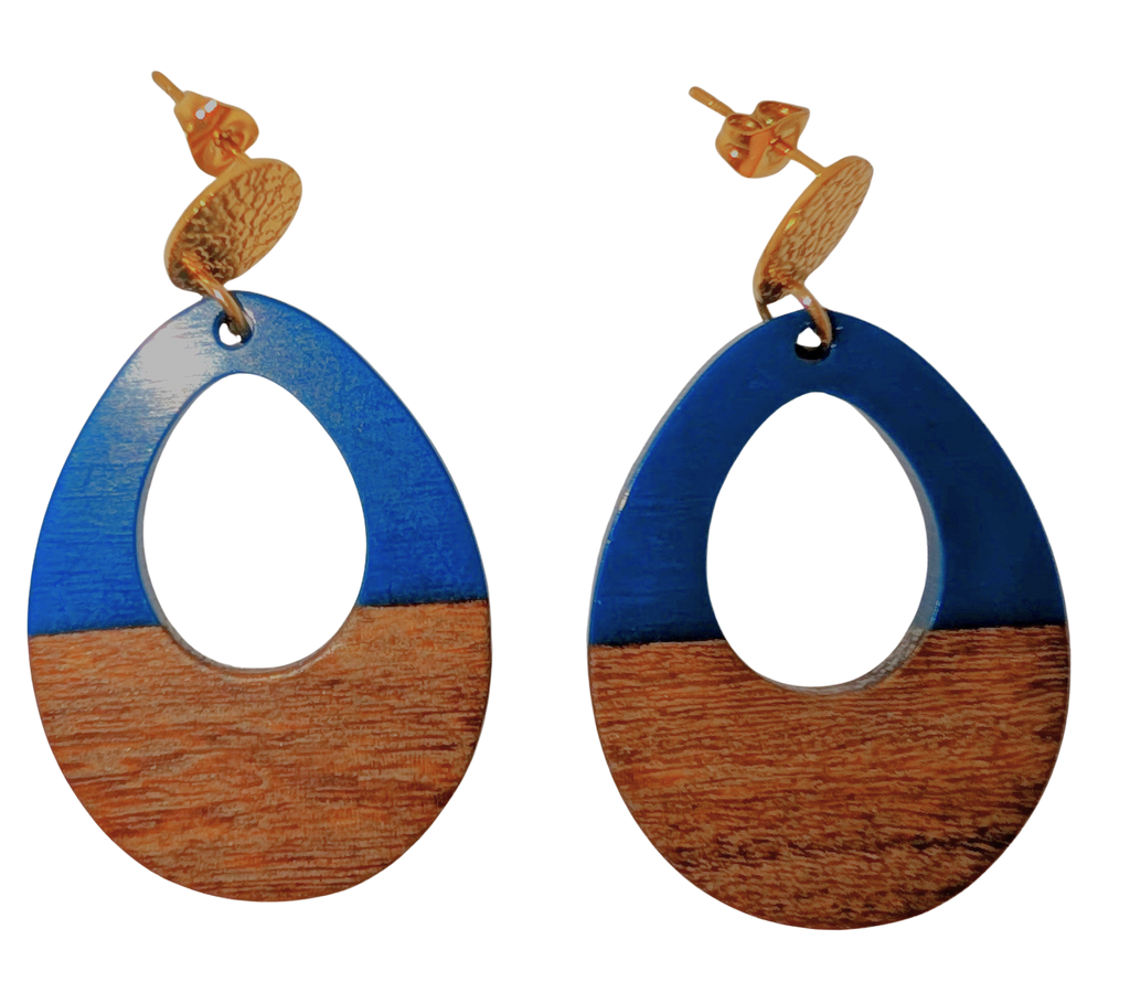 A pair of oval stud drop earrings with a cutout in the middle. The top half is blue and the bottom is walnut wood. Hardware is gold.
