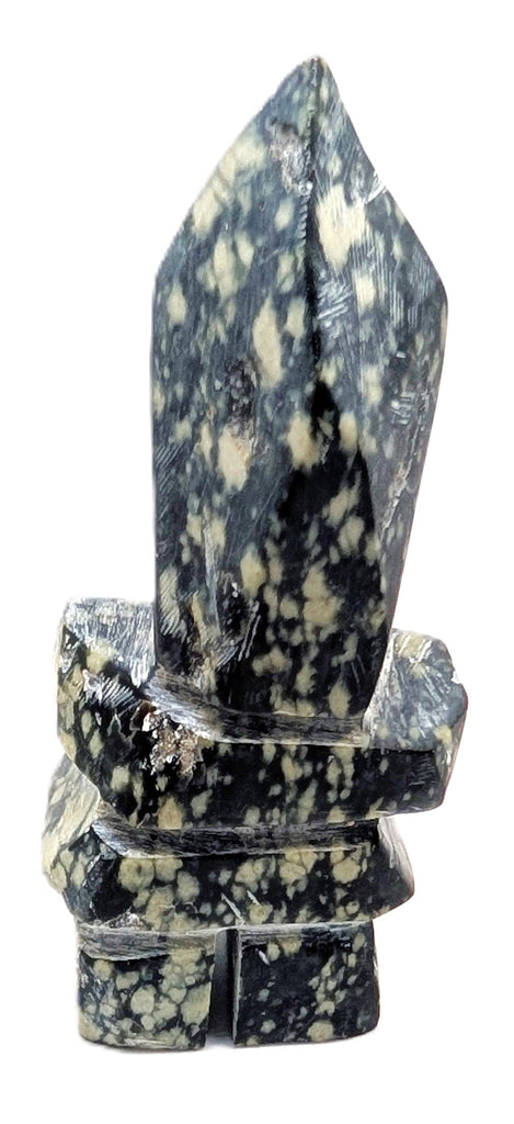 A black and pale green spotted inukshuk soapstone carving.