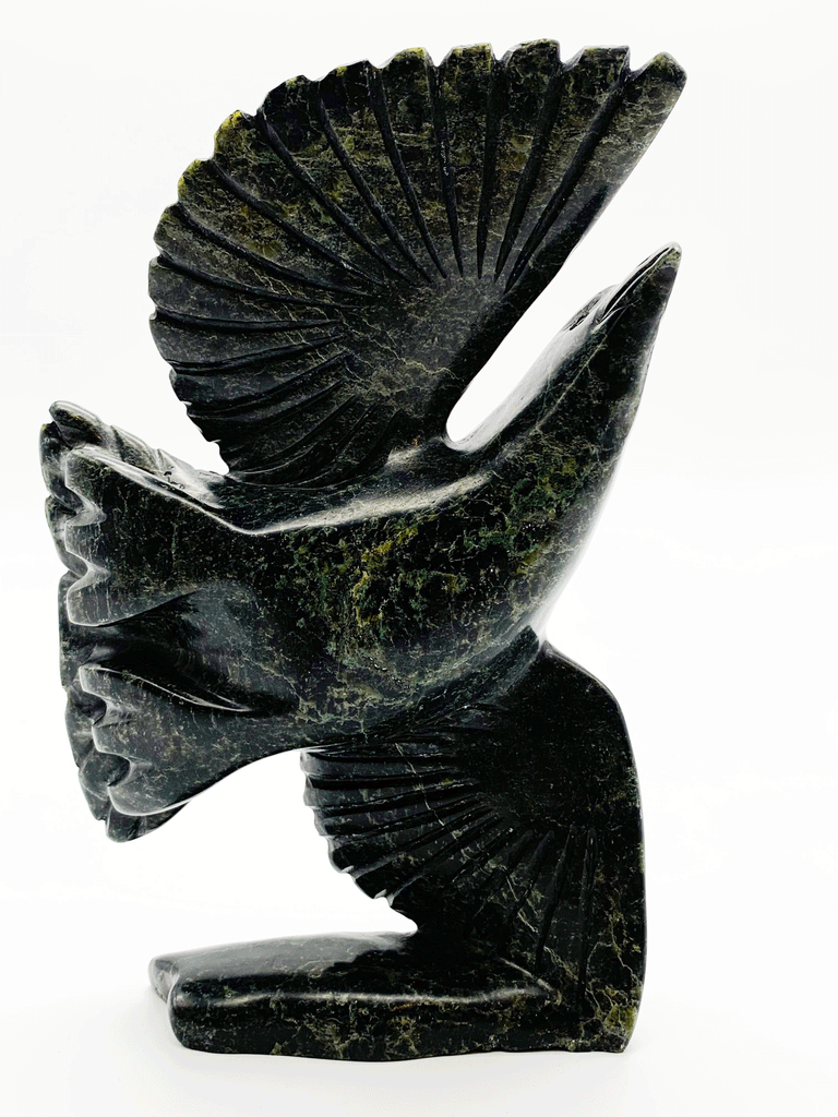 A black owl stands with wings pointing straight up, as if about to take off into flight. This image shows the detailed carvings of the underside of the wings and feet.
