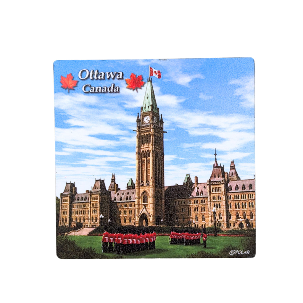 A square wooden magnet depicting the parliament building under a blue cloudy sky. Several Canadian guards can be seen standing on the green grass in front of parliament. 'Ottawa, Canada' is written in white in the top left, with red two maple leaves on either side.