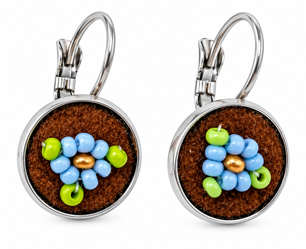 A pair of silver leverback earrings with round brown moose hide facepalm charms featuring blue and bronze beaded flower details, shown on a white background.