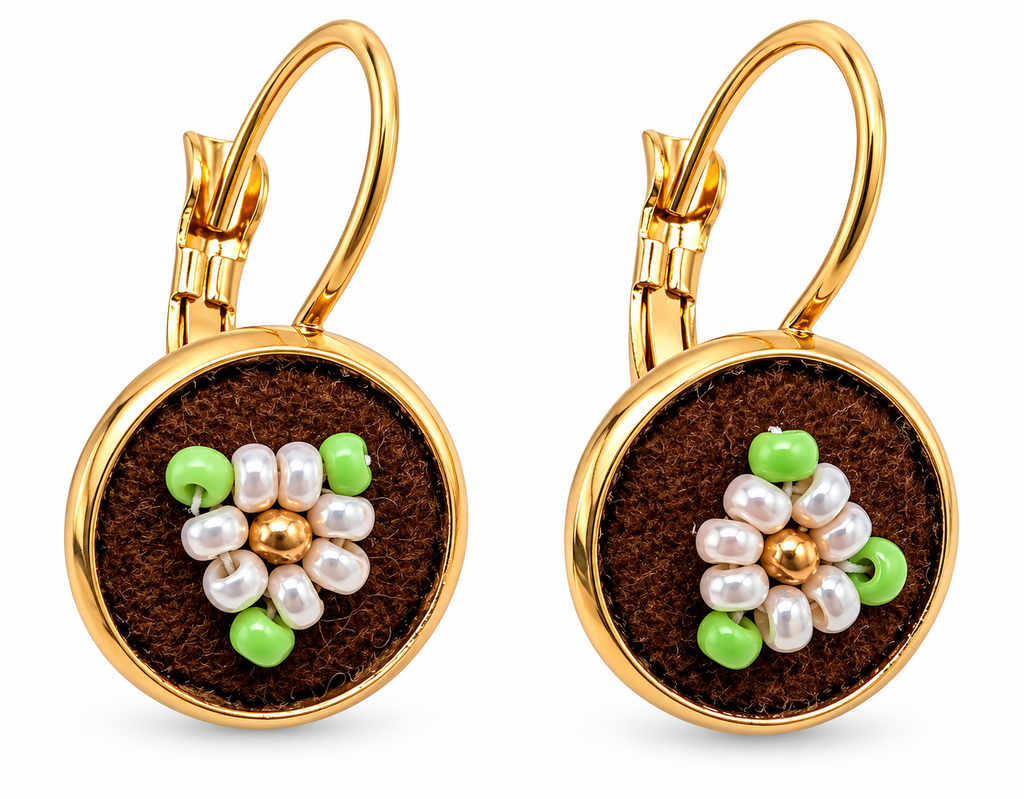 A pair of gold leverback earrings with round brown moose hide facepalm charms featuring white and green beaded flower details, shown on a white background.