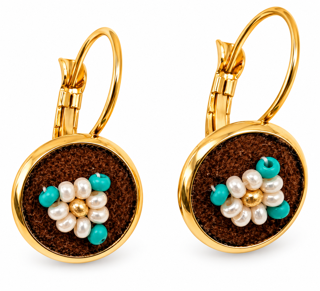 A pair of gold leverback earrings with round brown moose hide facepalm charms featuring white and gold beaded flower details, shown on a white background.