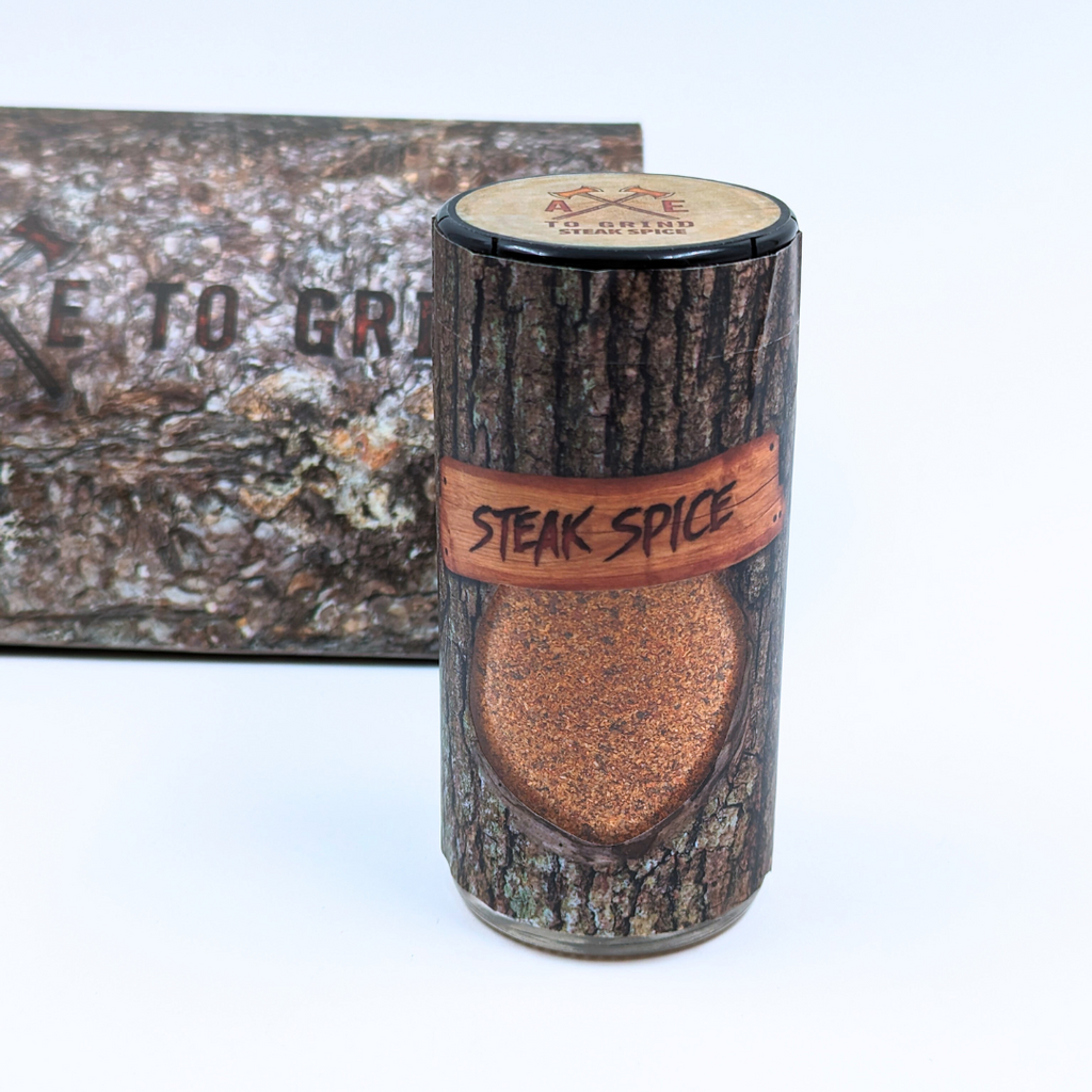 This spice blend is packaged in a reusable/recyclable glass jar printed to look like a log of firewood. The spice mixture is visible through a clear window in the packaging.