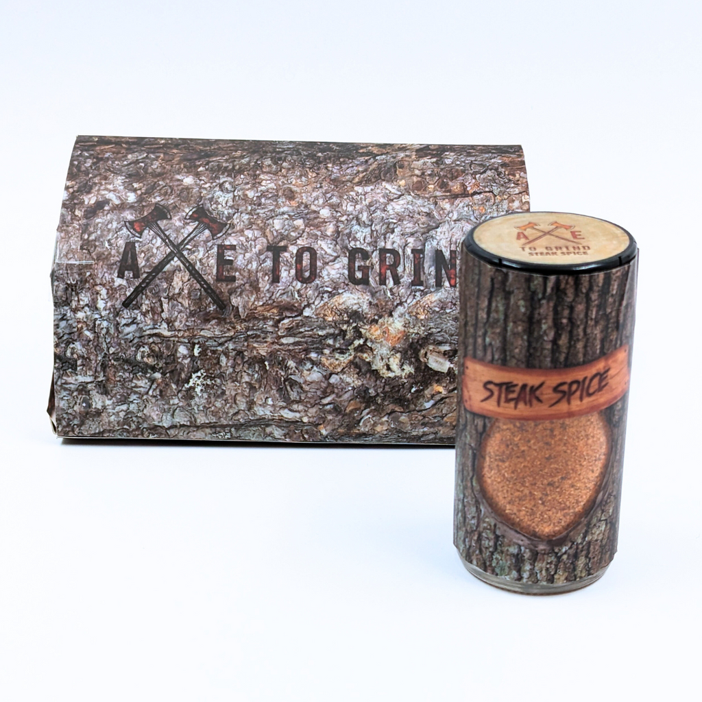 This spice blend is packaged in a reusable/recyclable glass jar printed to look like a log of firewood. The spice mixture is visible through a clear window in the packaging. Larger packaging  with "Axe To Grind" logo on box that looks like firewood.