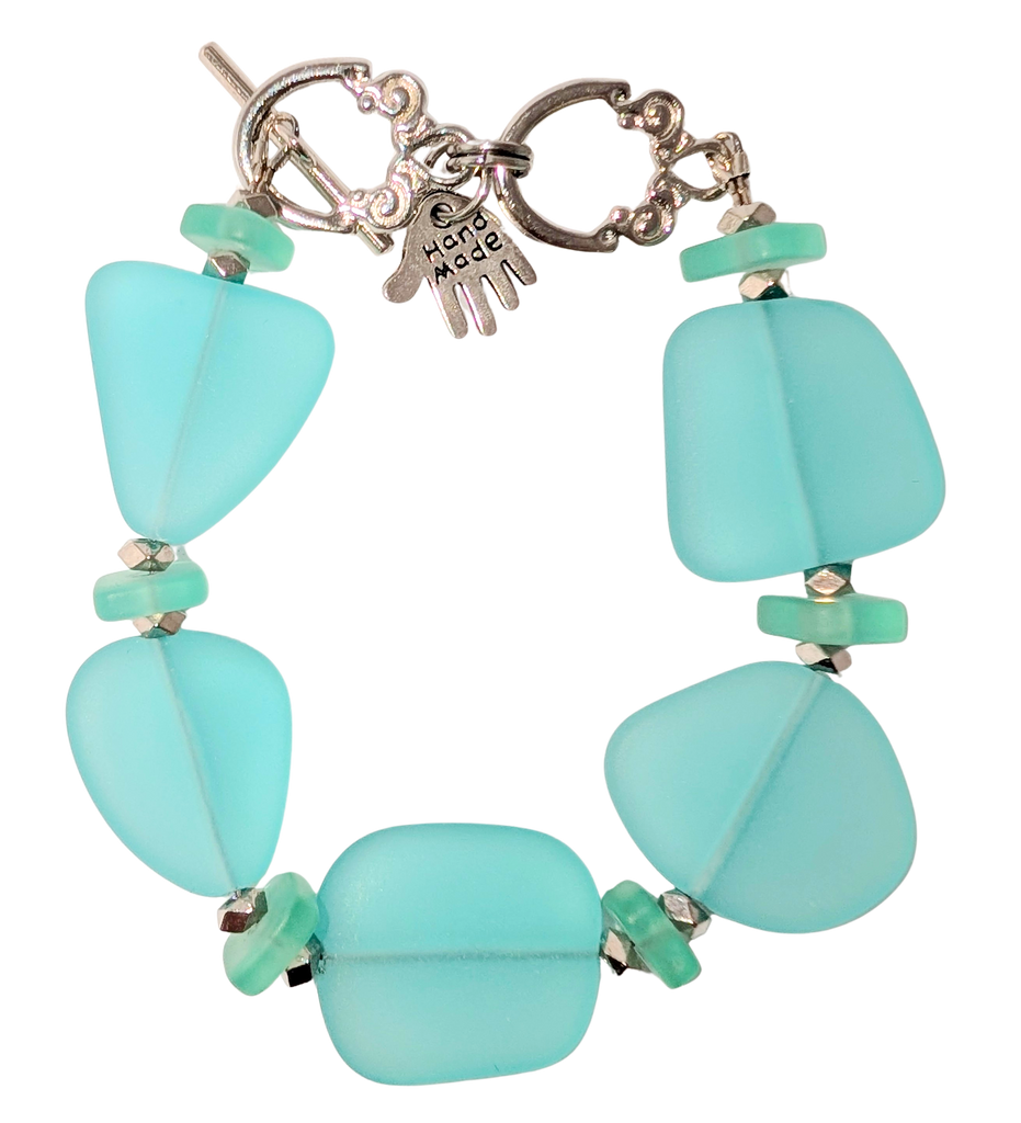 Bracelet with turquoise sea glass, beads, and a small hand charm that says "handmade" between 2 rings for sizing. The clasp is a silver toggle clasp.