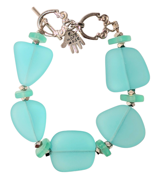 Bracelet with turquoise sea glass, beads, and a small hand charm that says "handmade" between 2 rings for sizing. The clasp is a silver toggle clasp.