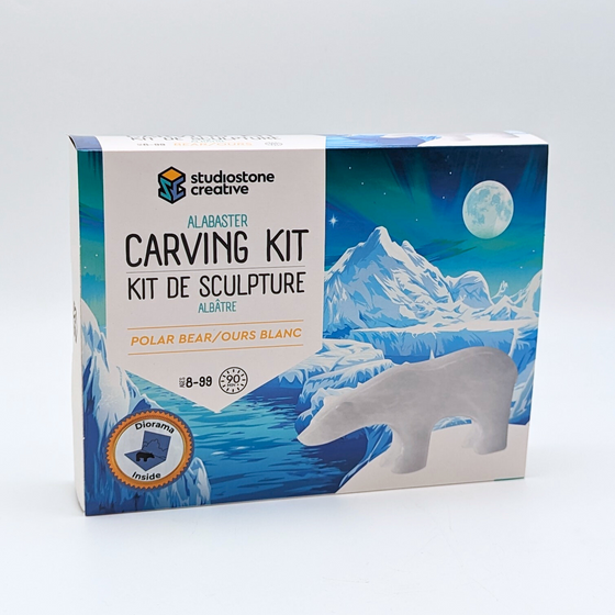 A box featuring an elegant, polished polar bear gainst a backdrop of a starkly beautiful glacier scene with the Northern Lights and a full moon. The banner featuring lettering reads "Alabaster Carving Kit: Polar Bear." It estimates 90 minutes to complete.