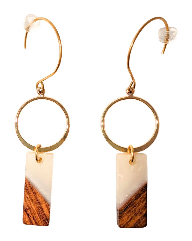 A pair of hook earrings. Earrings have a gold ring and hanging from it is a rectangular bead that is half white and half walnut wood. Hardware is gold.