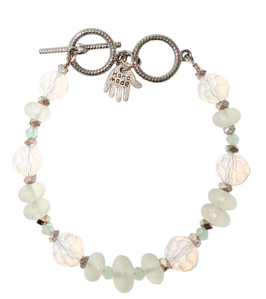 Bracelet with white sea glass, beads, and a small hand charm that says "handmade" between 2 rings for sizing. The clasp is a silver toggle clasp.