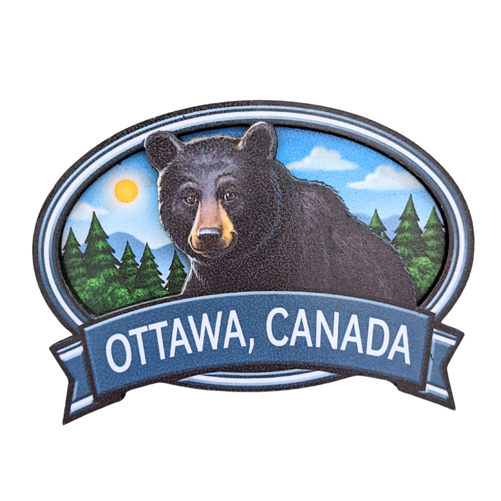 Dark blue bordered oval shaped wooden magnet. Vibrant Canadian black bear centered in a morning covered forest. "Ottawa, Canada" in white written underneath. on a blue ribbon banner.