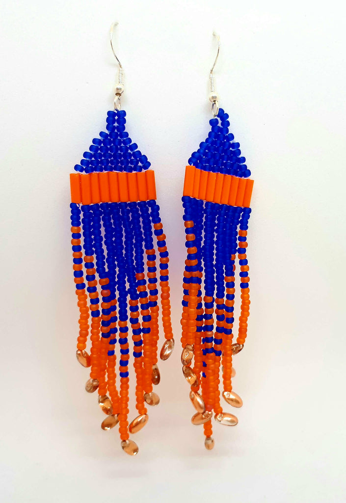 Orange and purple beaded earrings handcrafted by Inuk artist Mary Hunter. Earrings dangle from silver hook while alternating bead colours and sizes create bold pattern.