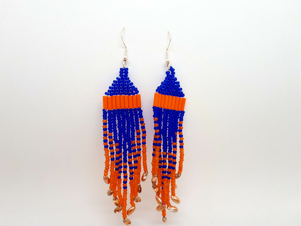 Orange and purple beaded earrings handcrafted by Inuk artist Mary Hunter. Earrings dangle from silver hook while alternating bead colours and sizes create bold pattern.