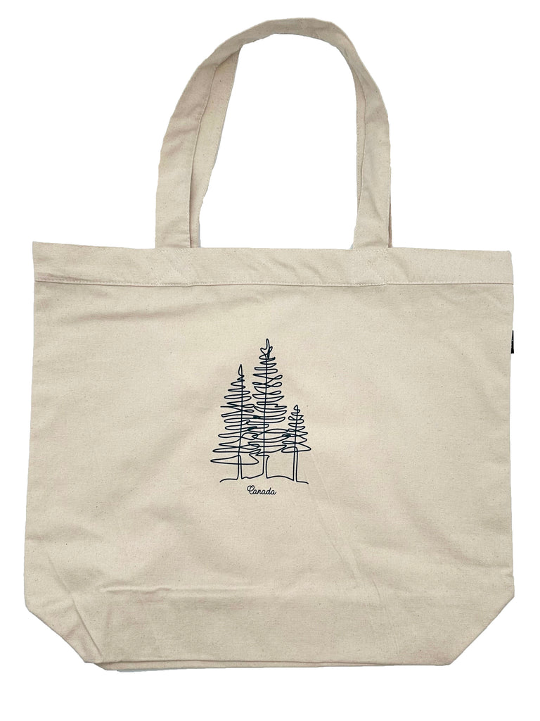 A light beige square tote bag with two handles at the top. Has a grain effect and a black line design of three trees. Underneath is written Canada in black cursive writing.
