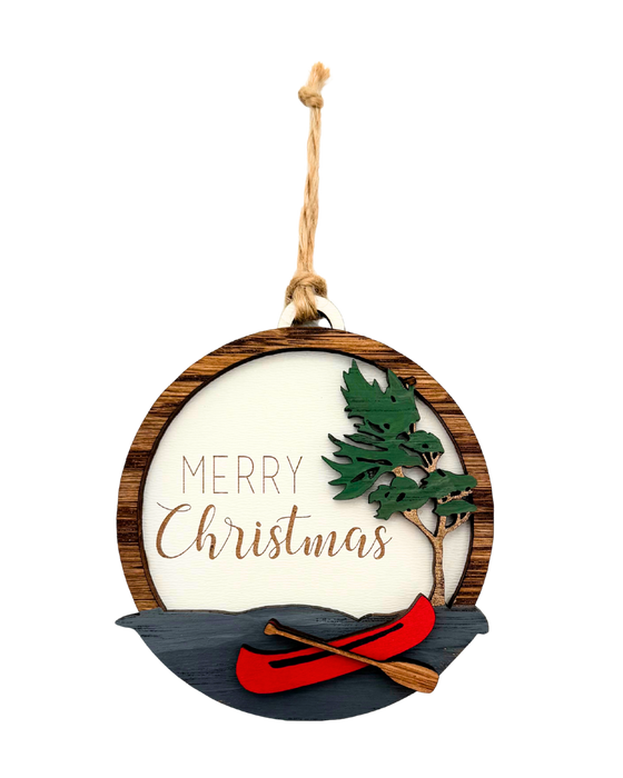 Christmas ornament with 'Merry Christmas' text, red kayak, and green tree.