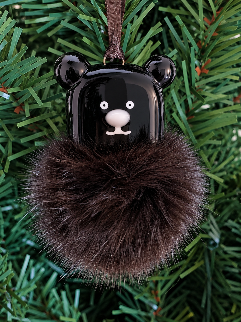 A fused glass black bear ornament with a furry black tail.
