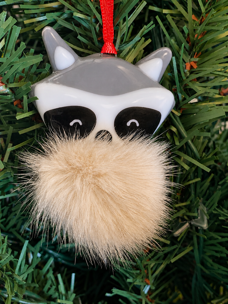 A fused glass raccoon ornament with a furry light beige coloured tail.