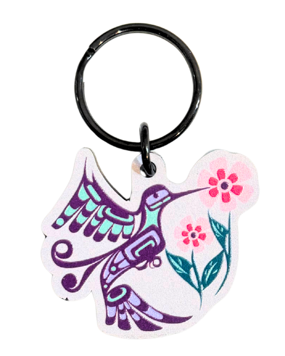 Keychain of a hummingbird next to flowers. Colours include Pinks, purple, and a light and dark tealish blue.