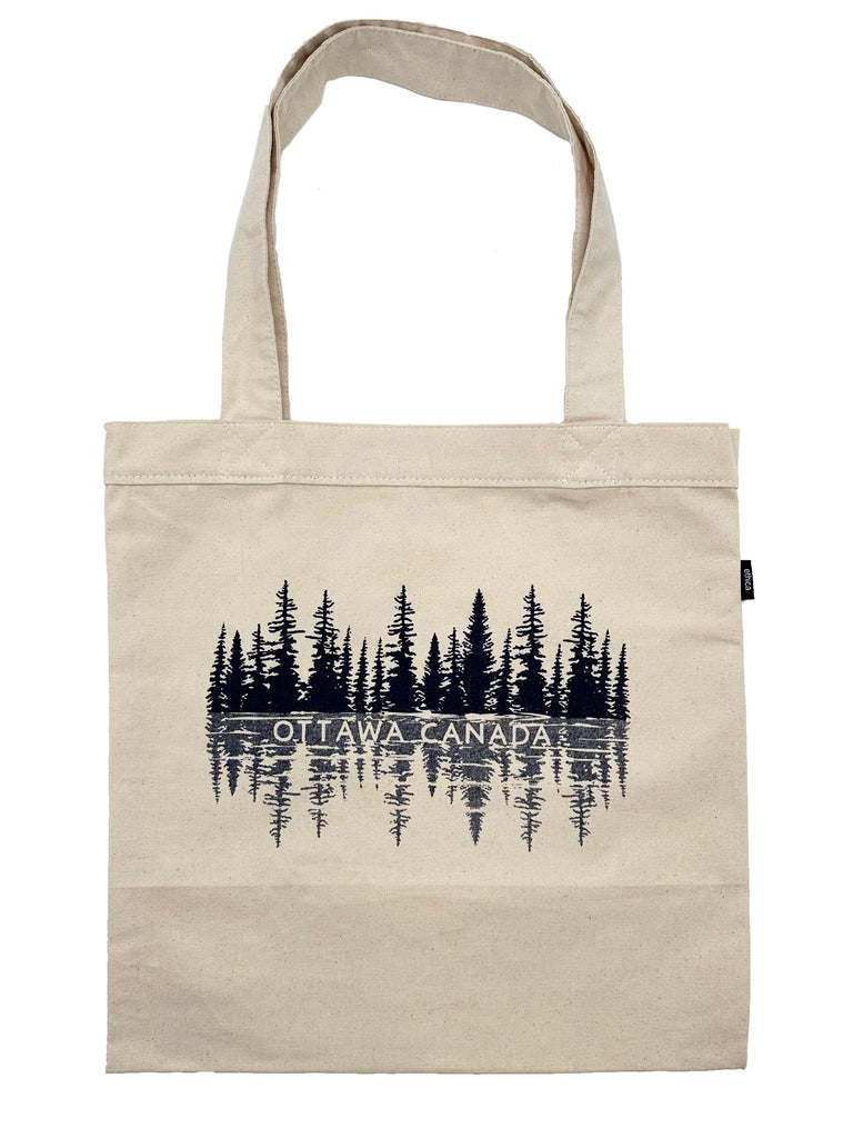 Pine trees reflected on a lake scene in dark blue with the words OTTAWA CANADA at the horizon line. Printed on a beige canvas tote.