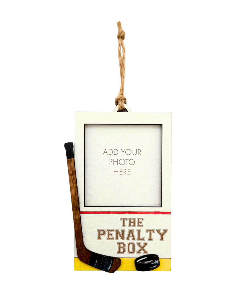 Hanging photo frame with hockey design labeled 'The Penalty Box'.