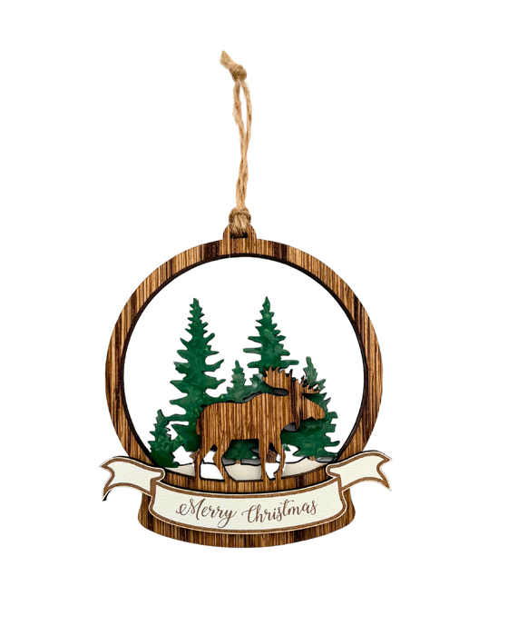 Wooden Christmas ornament with a moose and pine trees. Underneath reads 'Merry Christmas'.