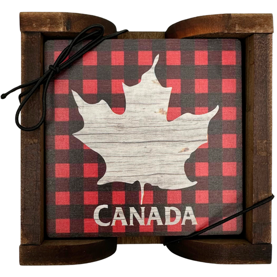 A square wooden coaster displayed in an attractive wooden holder. The coaster shows a maple leaf in distressed wood against a background of red and black plaid. Below the maple leaf, the coaster says "Canada"