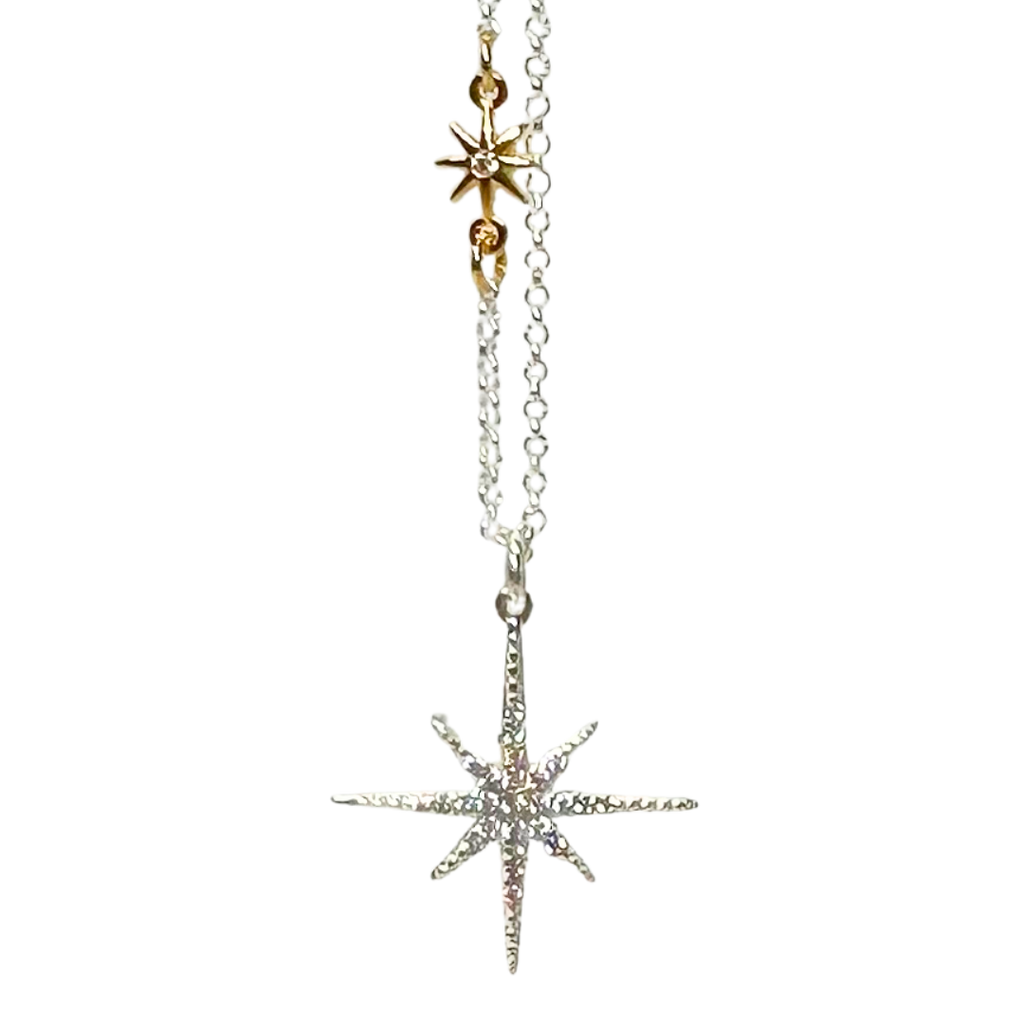 Silver chain with small gold star with eight even points attached in the middle of the of the chain. Gold star is symmetrical. Larger star is the pendent with jewels covering the top surface. Silver star also has 8 points. The points that point up, down, left, and right are longer. 