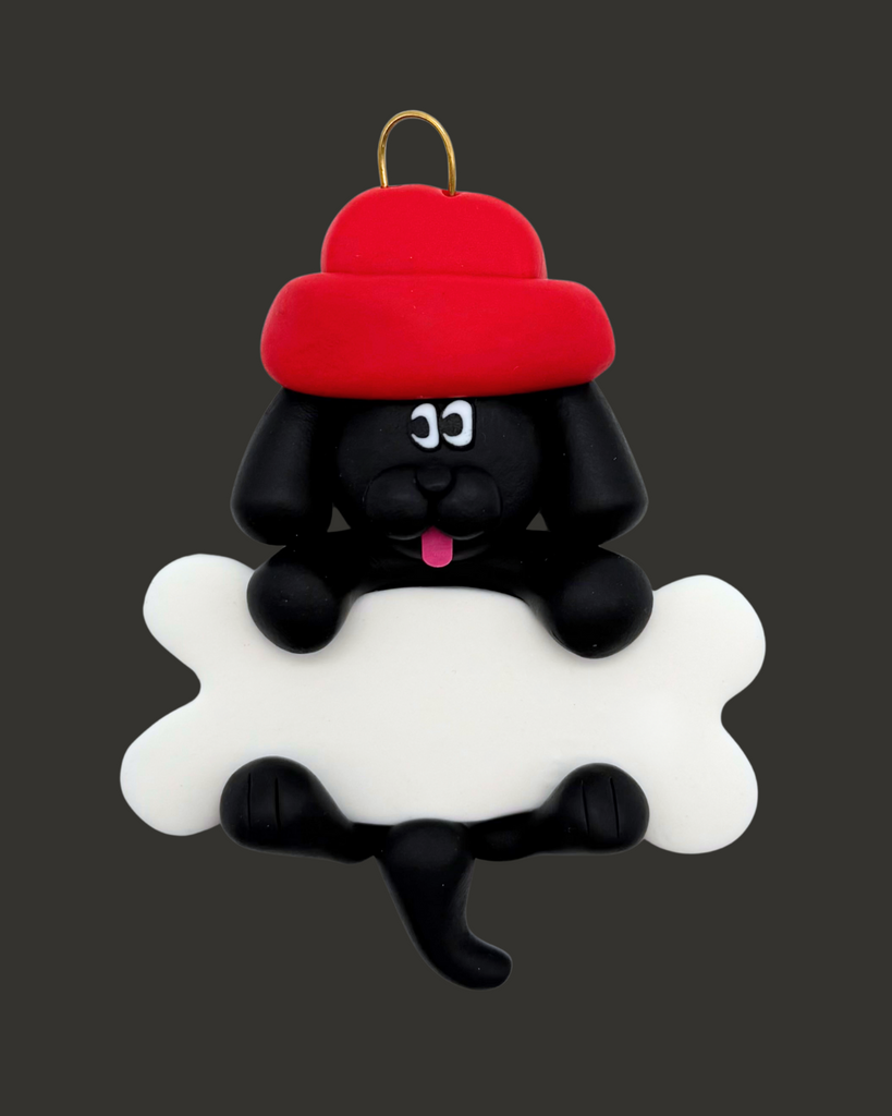 Black dog ornament with a bone wearing a red hat on a black background.