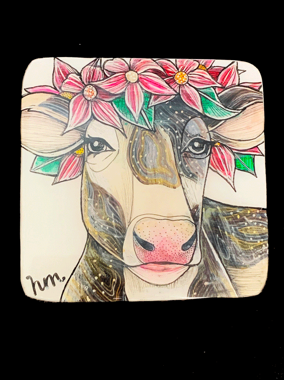 A cow wearing pink flowers and green leaves on its head is surrounded by a white background.