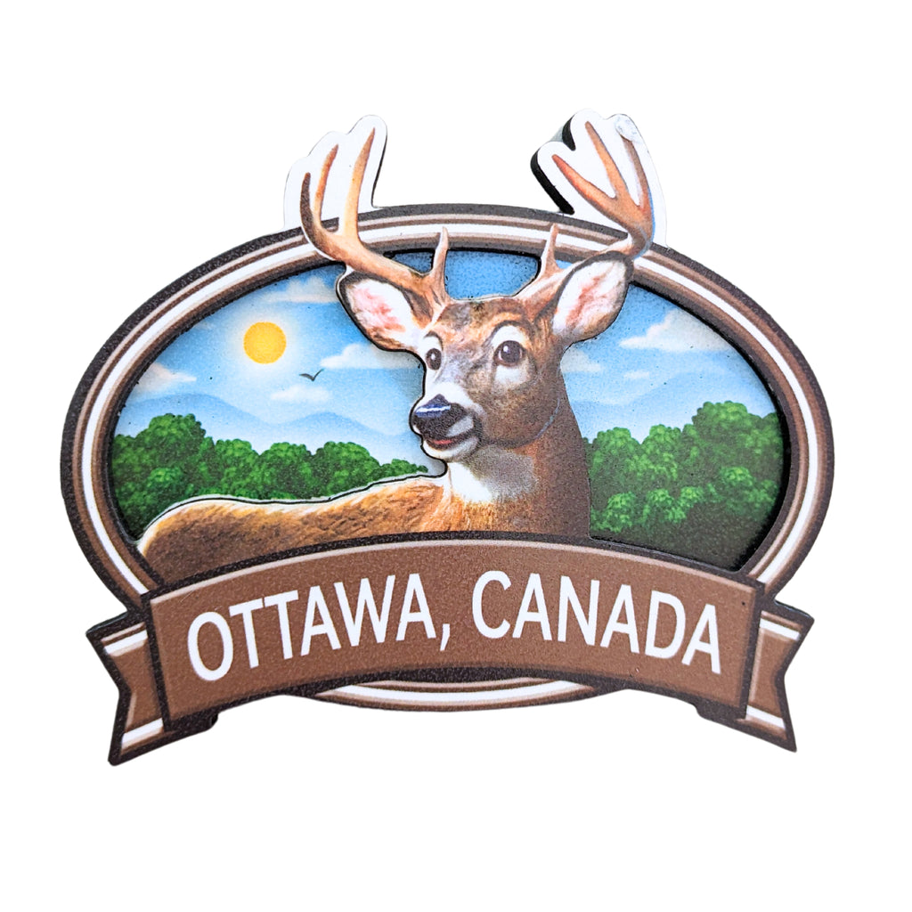 Brown bordered oval shaped wooden magnet. Vibrant Canadian buck/deer centered in a morning covered forest. The antlers embedded in the boarder above the edge. "Ottawa, Canada" in white written underneath on a brown ribbon banner.