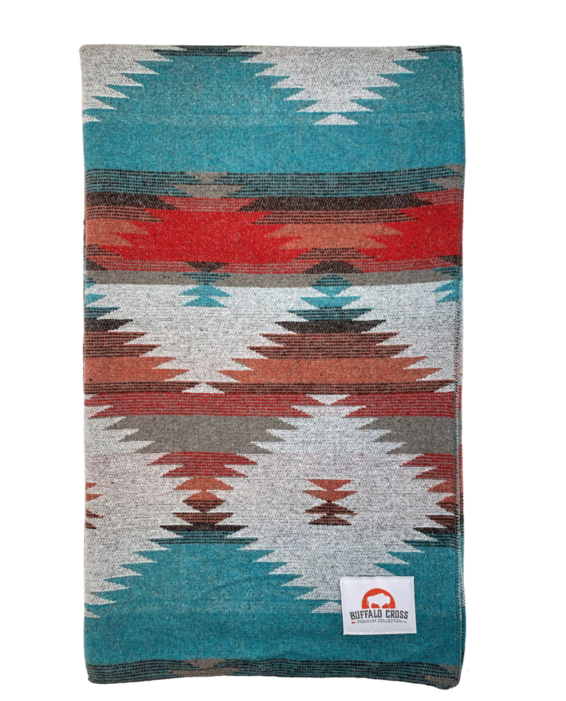 A blanket with a diamond pattern. Colours consist of grey, red, blue, orange and black.  Has patch of Buffalo Cross logo. Patch is white with orange accent and black text.