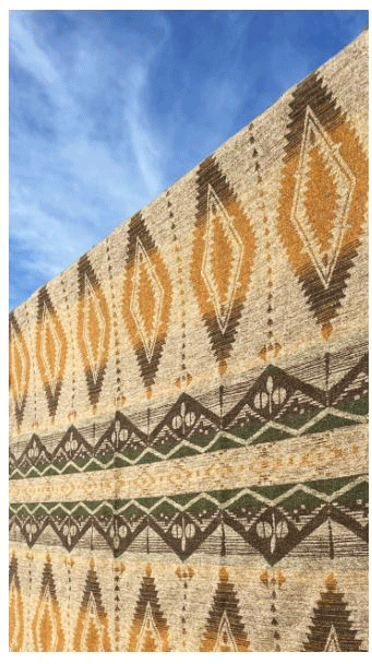A blanket with diamond patterns. Colours consist of brown, grey, yellow and green.