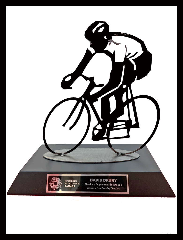 A dynamic cyclist depicted in line drawing and silhouette is mounted to a trapezoidal black base. On the base is a black and gold plaque with the logo and company name for Fighting Blindness Canada and the plaque reads "David Drury Thank you for your contributions as a member of our Board of Directors."