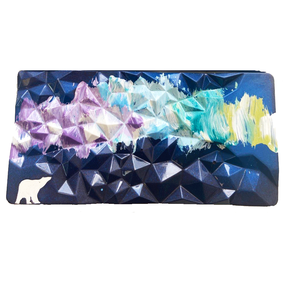Rectangle chocolate bar with geometric surface. Hand painting of a polar bear and northern light sky. Dark blue sky with light green, yellow, purple, and light blue nothern lights. White polar bear.