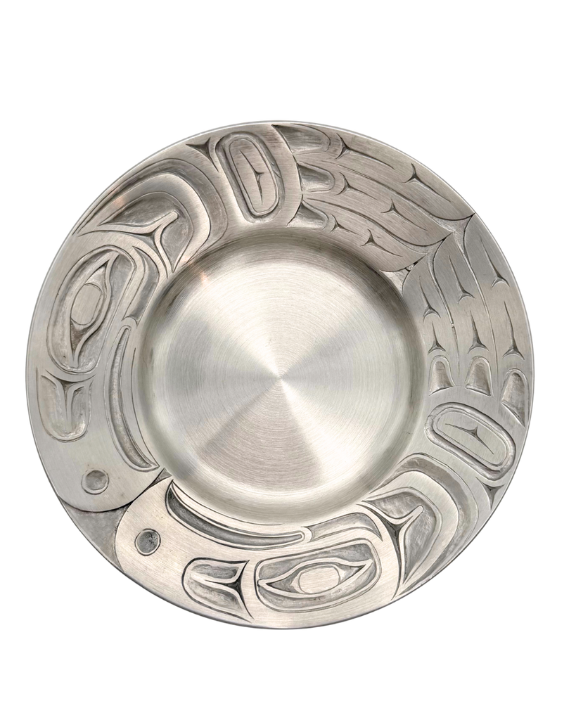 Silver pewter plate with carved eagle patterns along the edge.