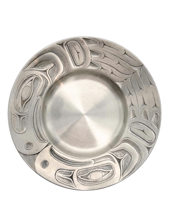 Silver pewter plate with carved eagle patterns along the edge.