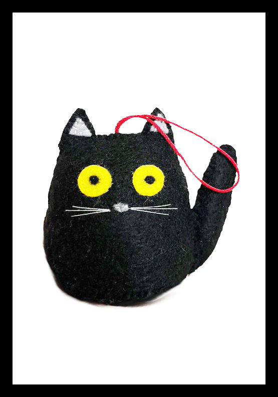 A handcrafted ornament of a black cat with yellow eyes and white whiskers in Canadian icon Maud Lewis' signature art style. The cat waves its left paw.