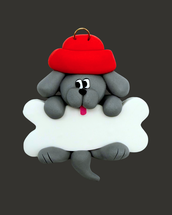 Grey dog ornament with a bone wearing a red hat on a black background.