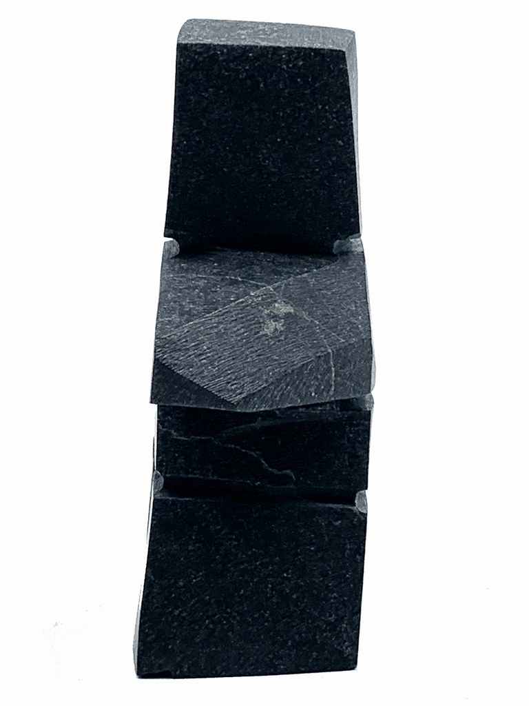 An angular, tapered inukshuk carved in black stone.