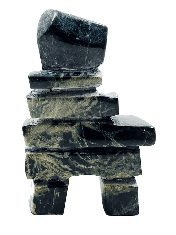 An inukshuk made of five slender slabs stacked on top of two broad legs and topped with a large head. The stone is vividly contrasting green and black. 