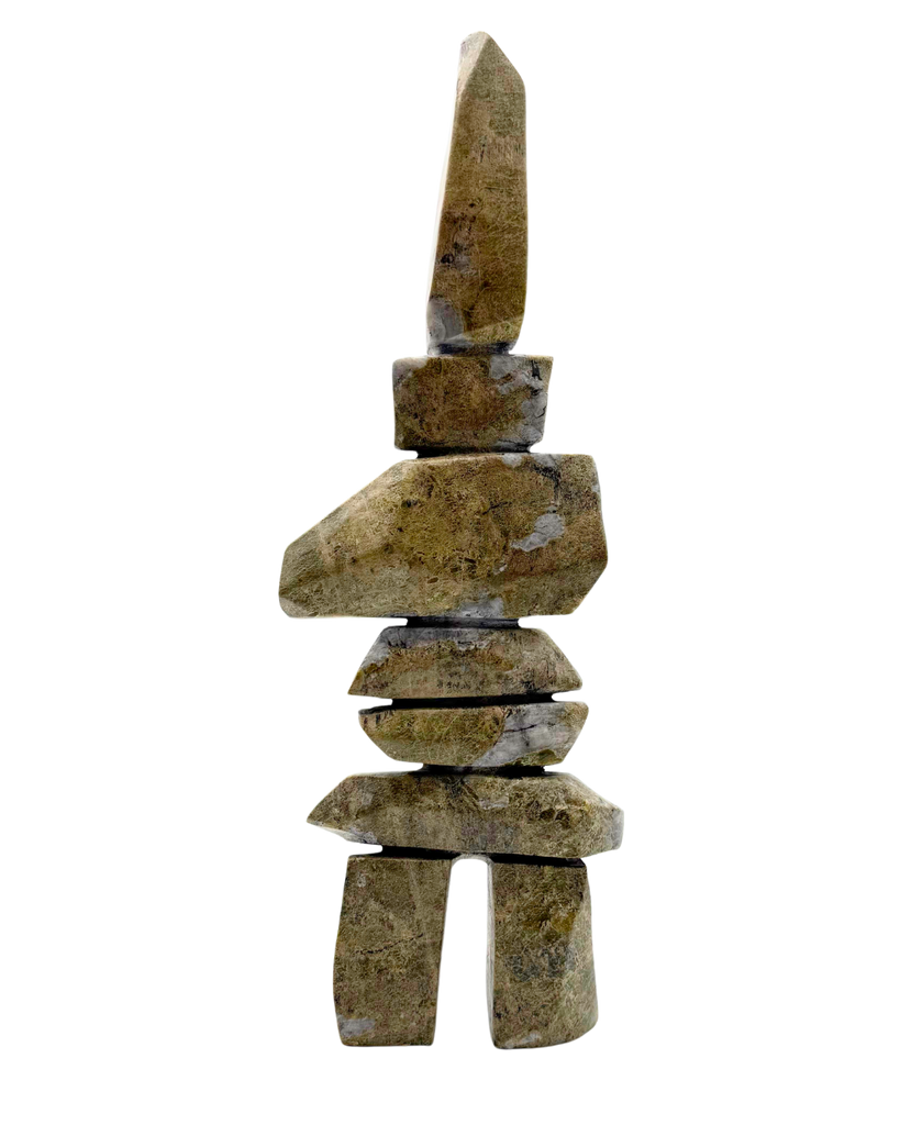 A tall inukshuk carved from greenish-brown stone.