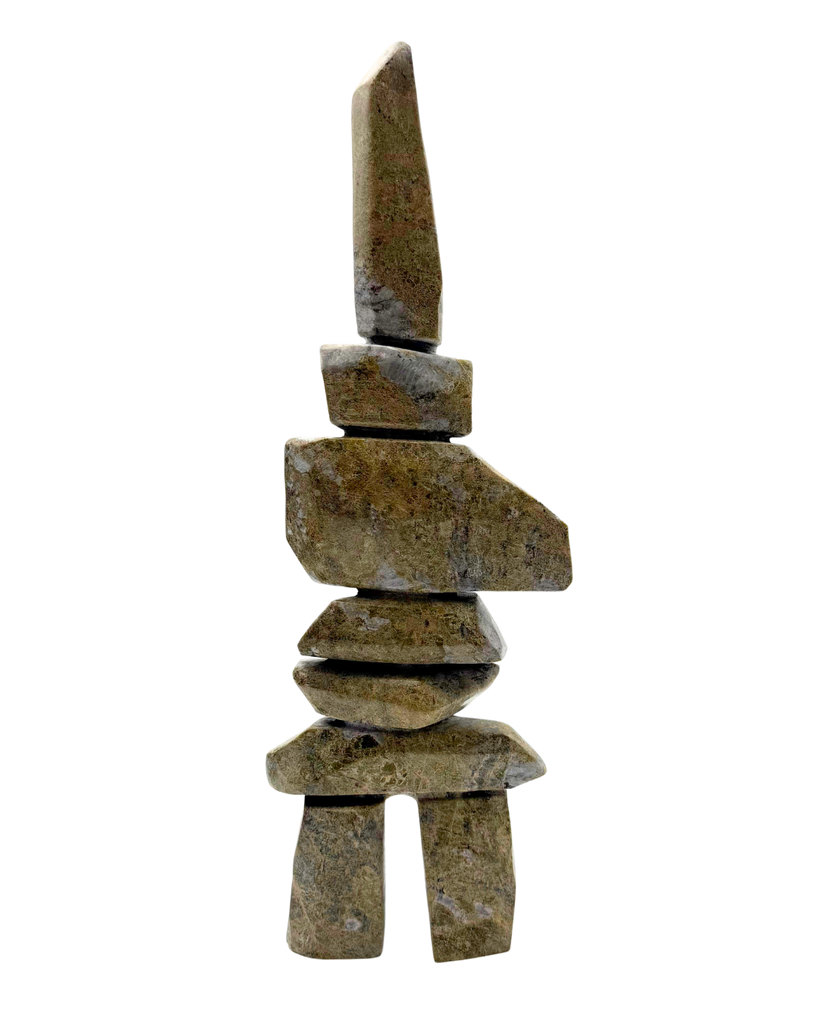 A tall inukshuk carved from greenish-brown stone.