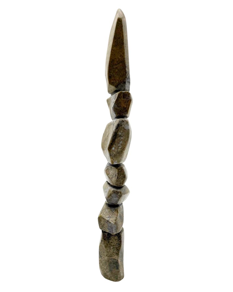 A tall inukshuk carved from greenish-brown stone.